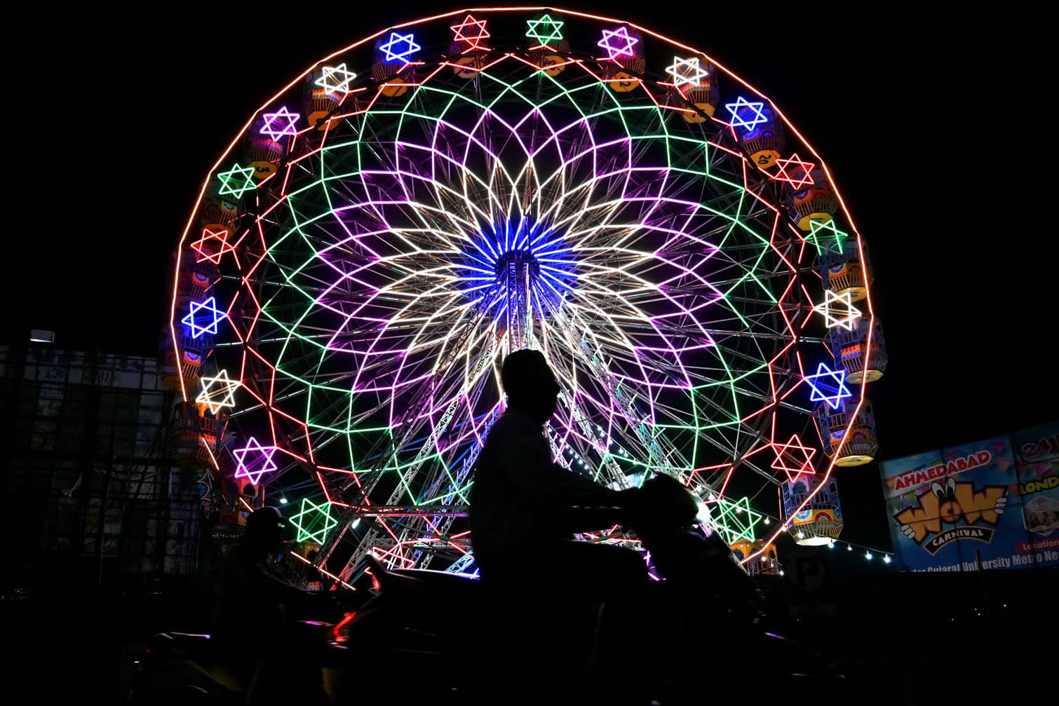 A man rides a scooter past a Ferris wheel