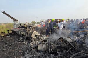 Rescue personnel and onlookers gather around the wreckage of an aircraft