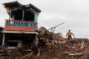 A man stands by the rubble of a house