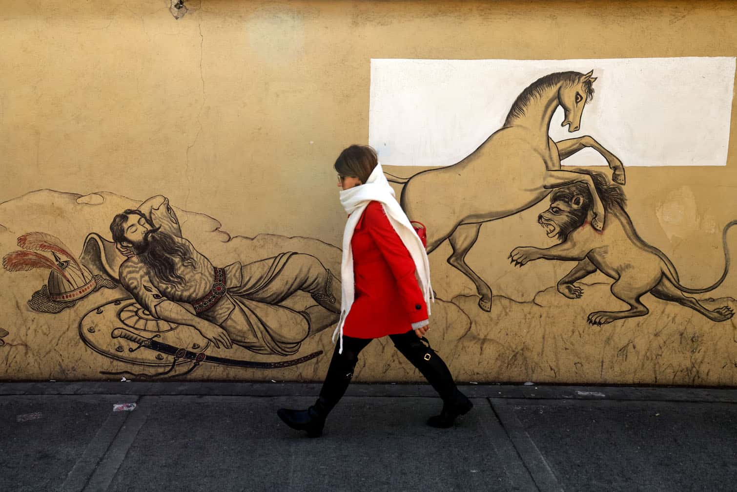 An Iranian woman walks past a mural