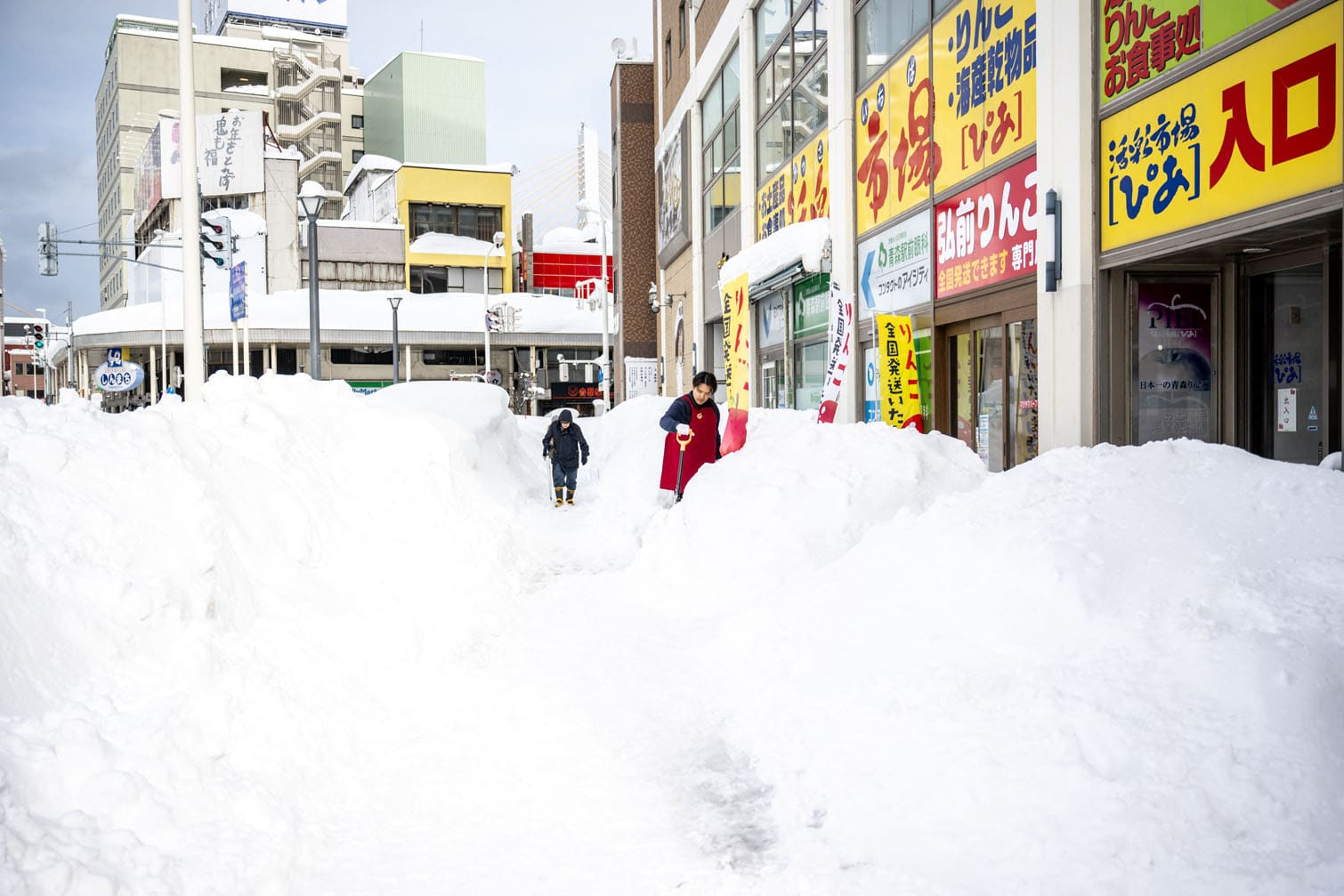 A shop employee (R) shovels the snow