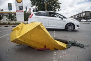 A vehicle passes a massive hole in the road