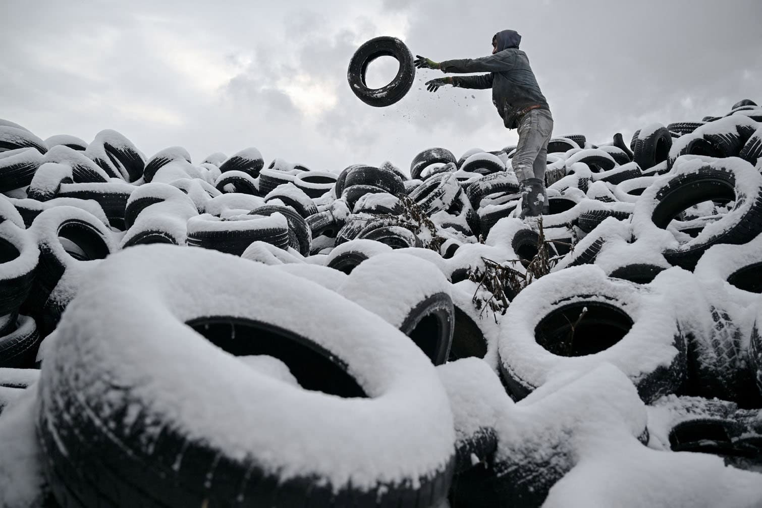 A worker arranges a pile of discarded tires