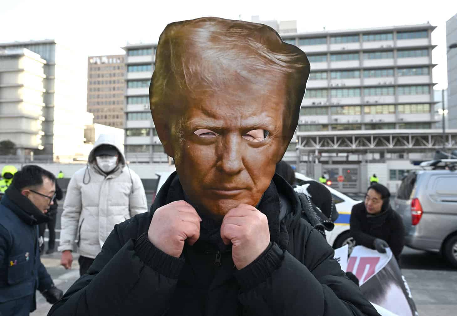 A protester wears a mask of US President Donald Trump