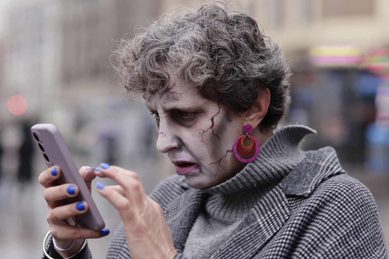 A person dressed as a zombie uses her phone