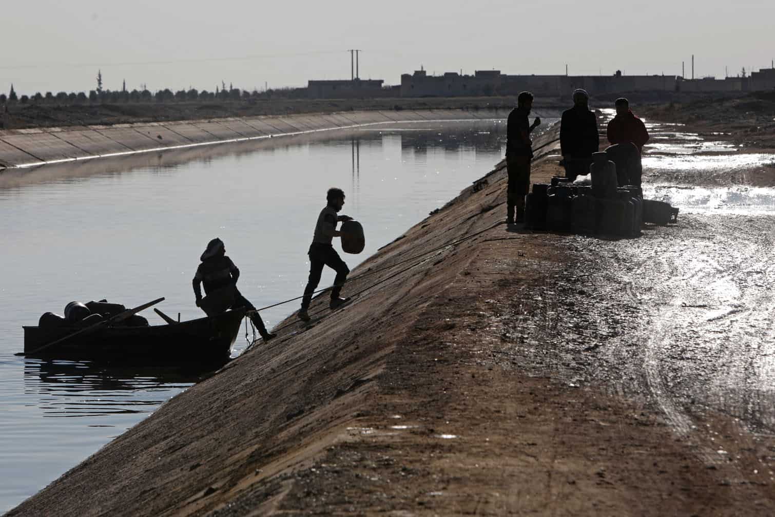 People along with their belongings use a boat to flee from a Kurdish-controlled area