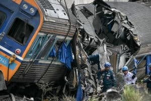 Recovery workers stands next to the wreckage of a train