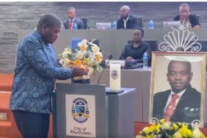 Executive Mayor Nkosindiphile Xhakaza lights a candle in memory of MMC Andile Mngwevu at the Council Chambers. Picture: City of Ekurhuleni. Screenshot.