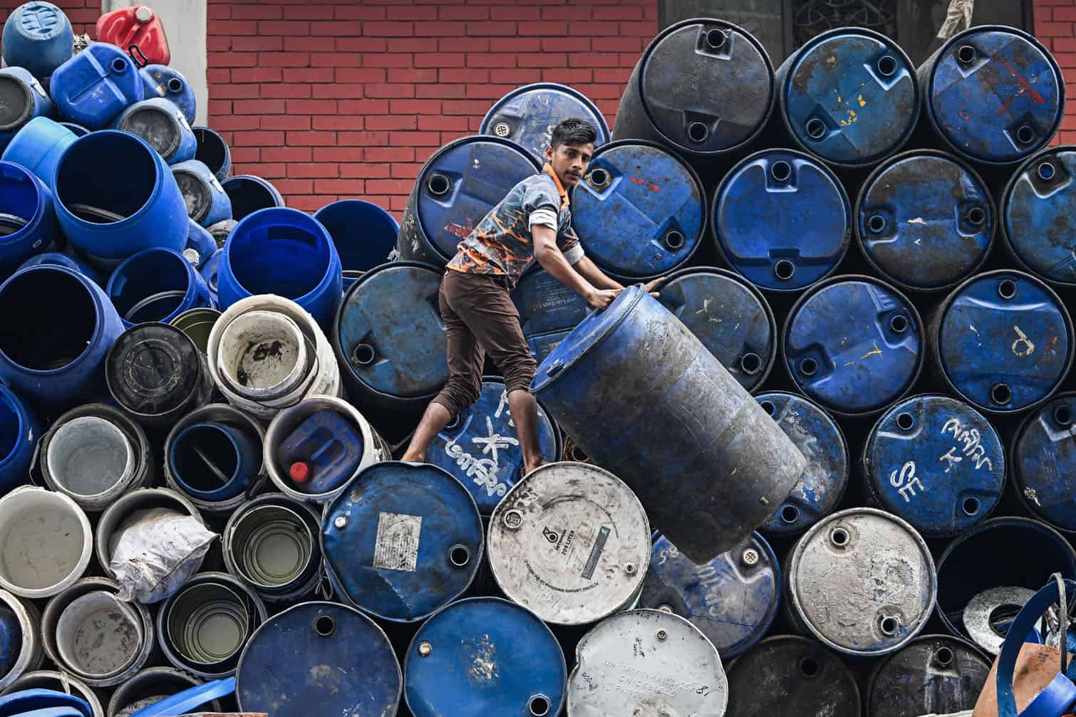 A worker stacks empty drums outside a shop