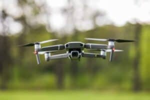 Quadcopter flying on a clear sunny green day background with nice lens flare.