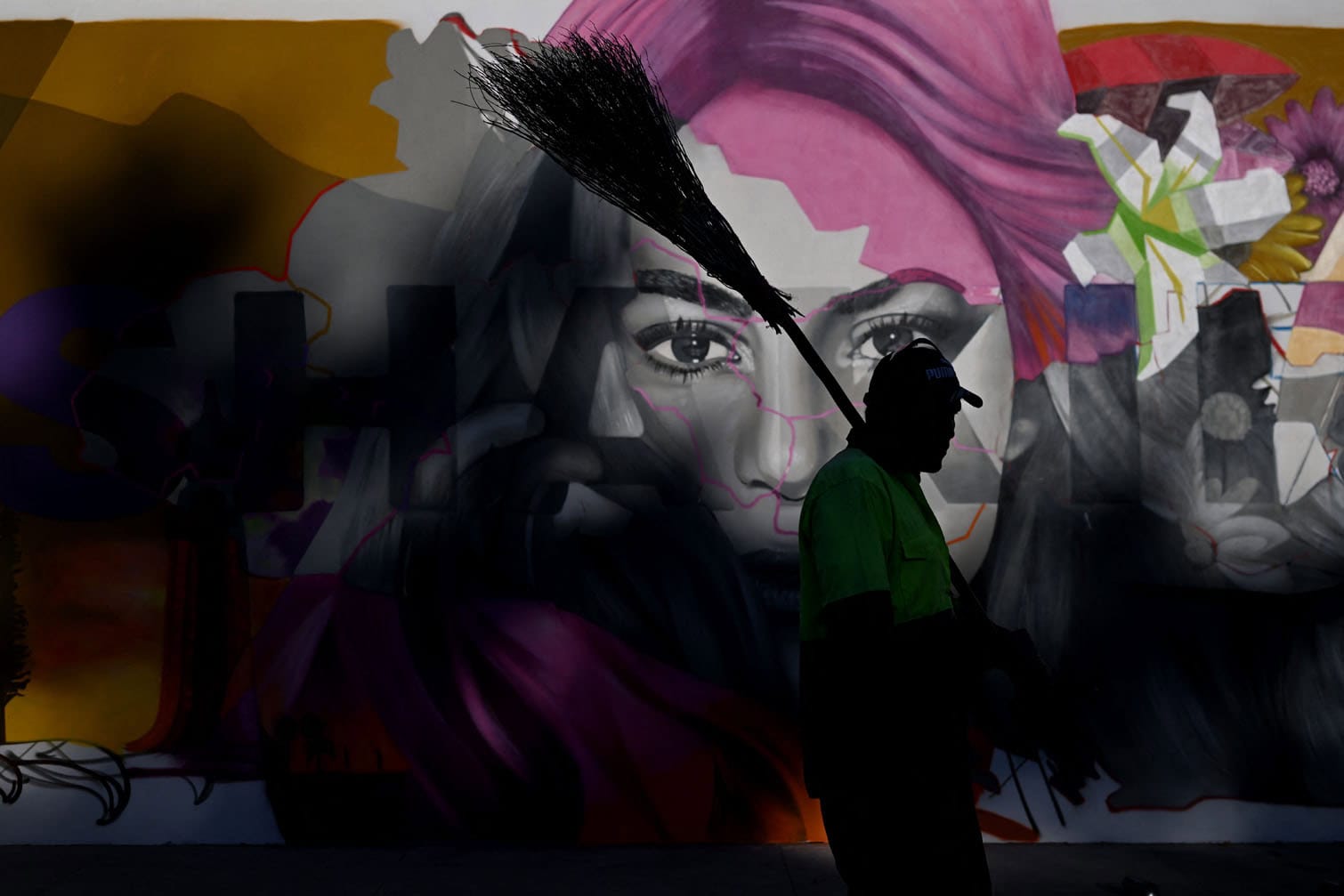 A municipal worker walks past a mural depicting Colombian singer Shakira