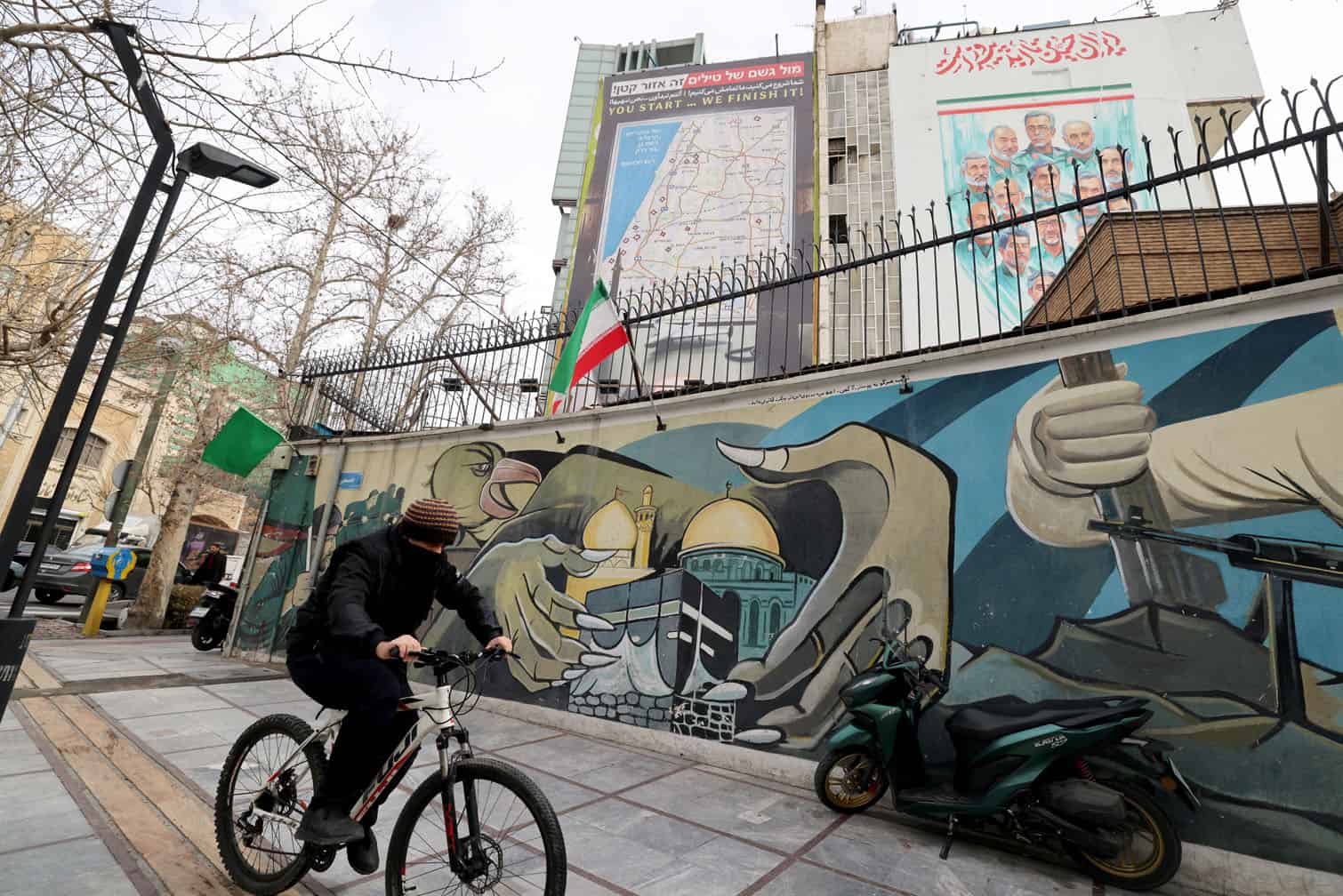 A man cycles past a mural and a giant billboard