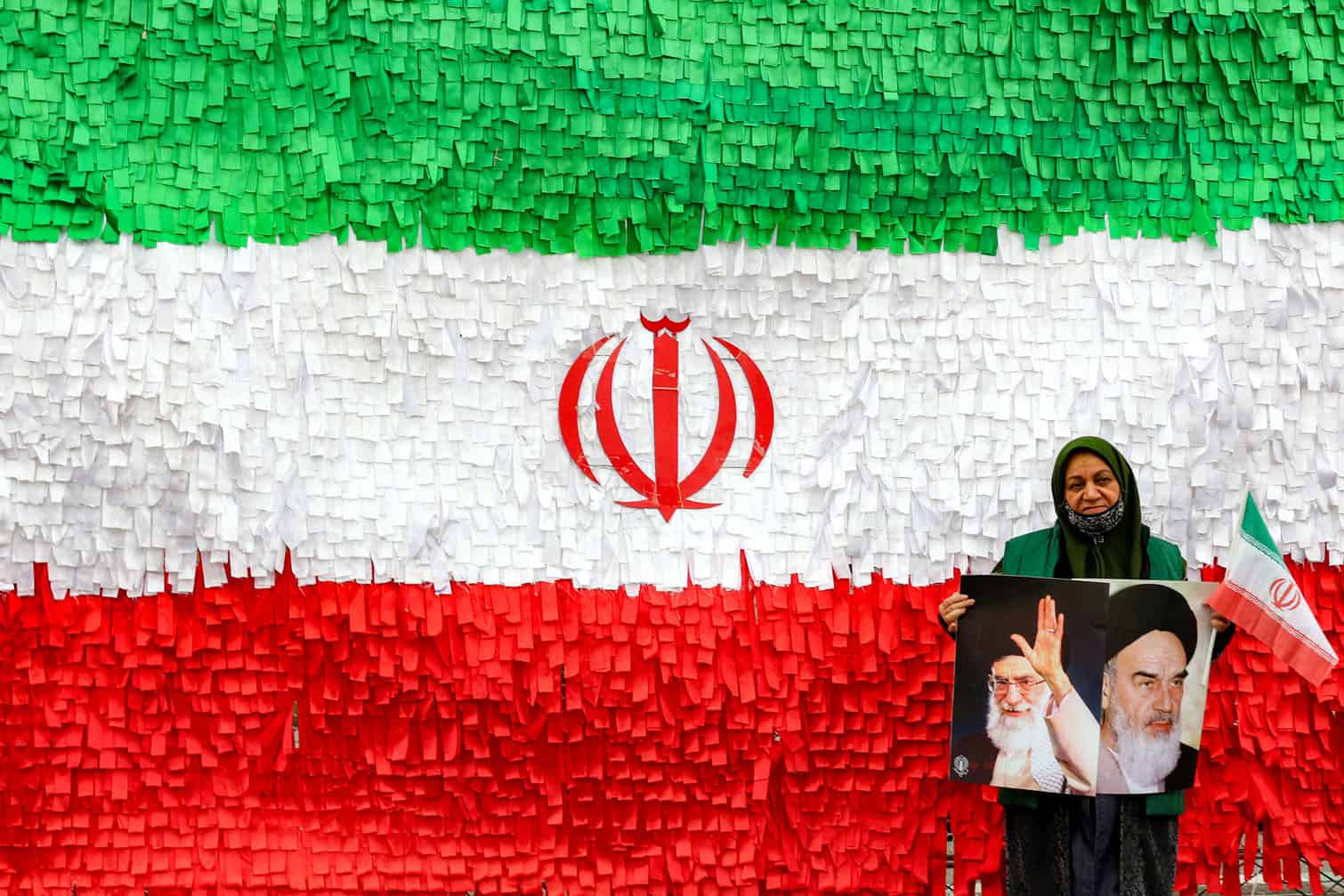 A woman poses with the pictures of Iran's late and current supreme leaders
