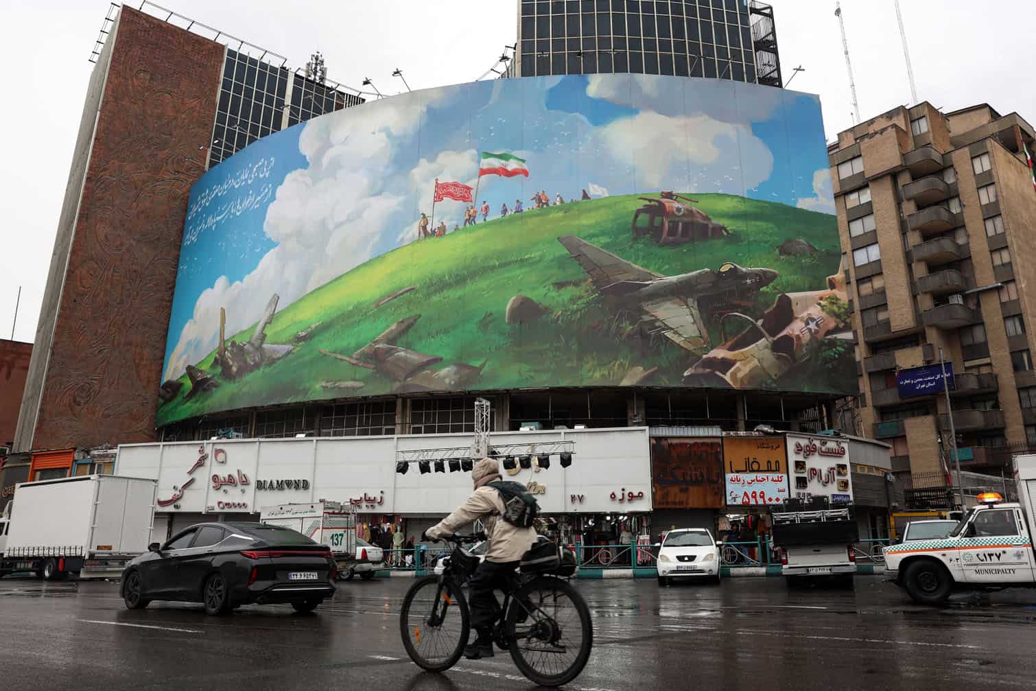 A cyclist rides past an anti-US billboard