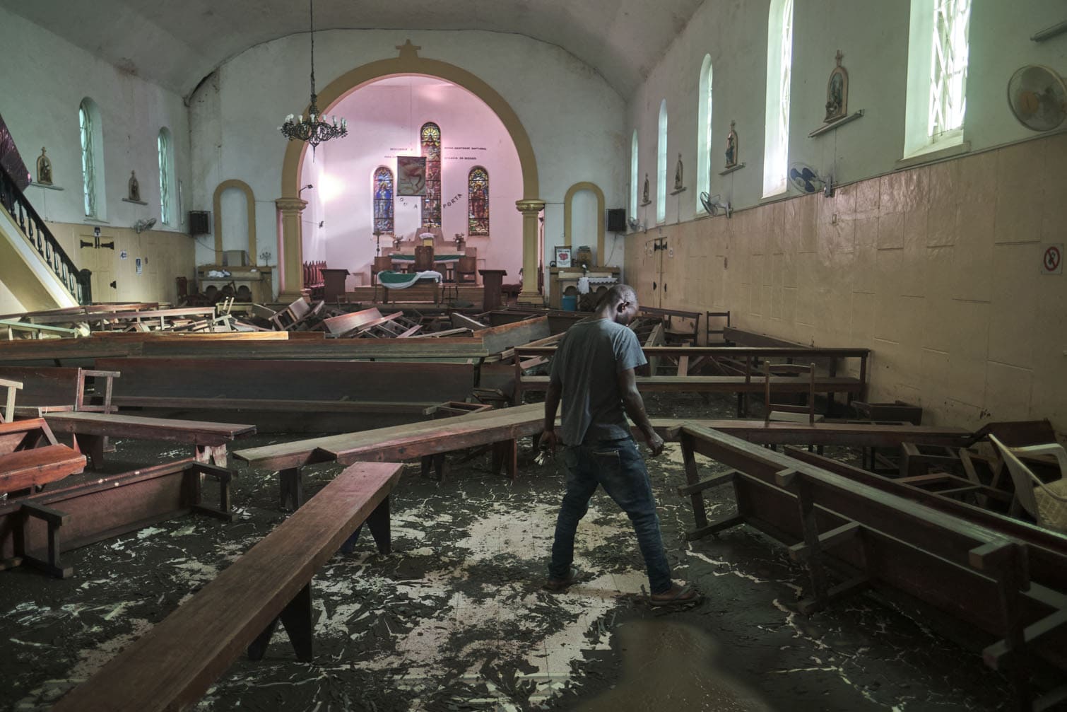 A caretaker walks amid benches scattered by flooding