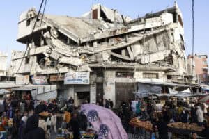 Palestinians shop for food beneath a destroyed building in Gaza City
