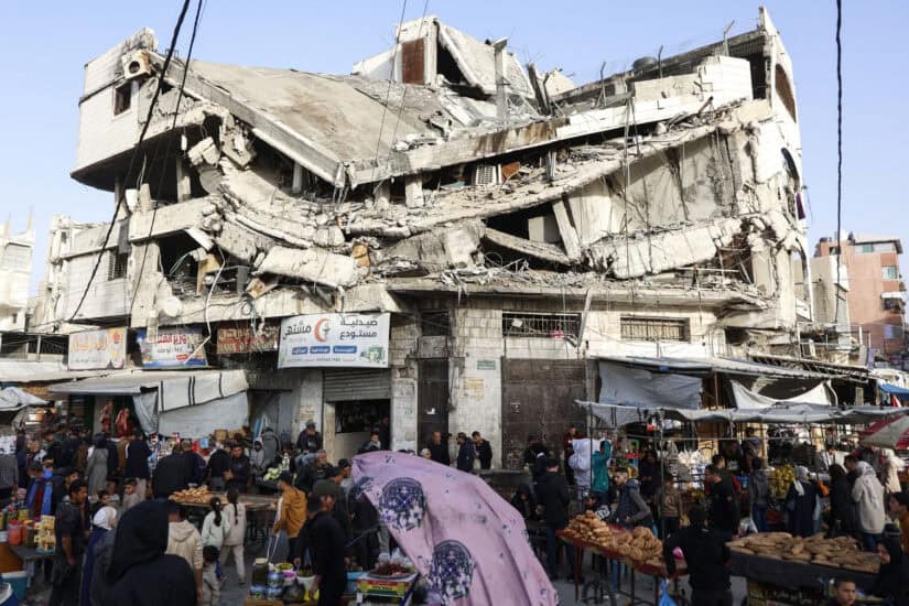 Palestinians shop for food beneath a destroyed building in Gaza City