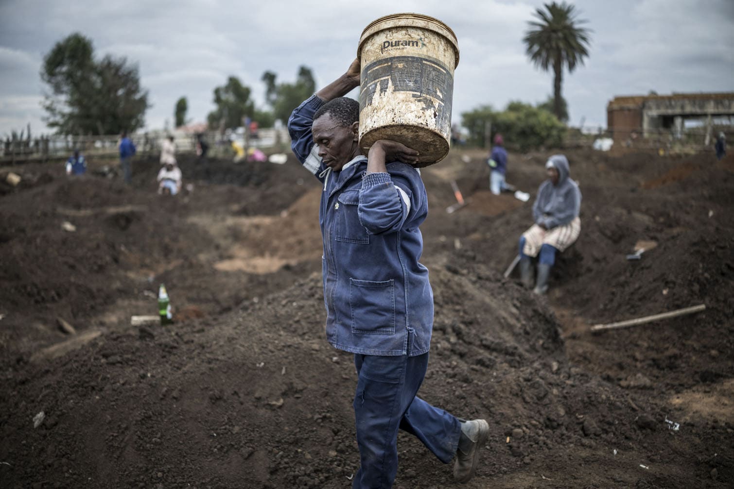 A man carries a bucket full of soil