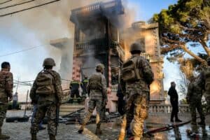 Lebanese army soldiers and civil defence members inspect a burnt building