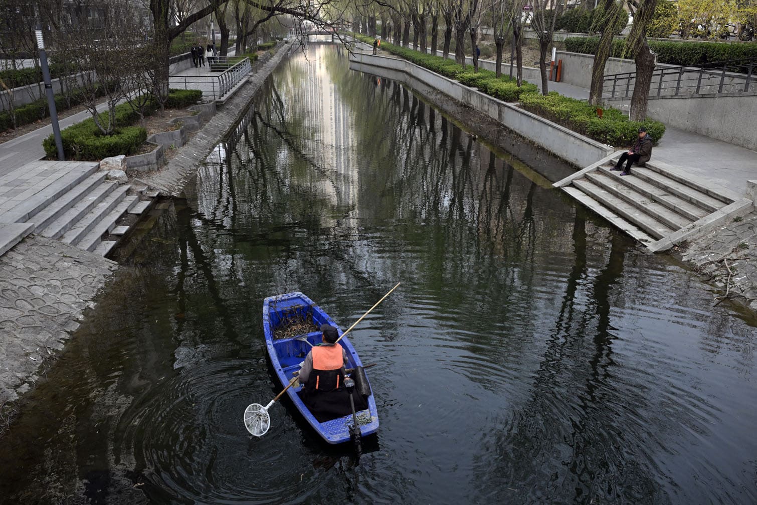 A worker on a boat cleans the Liangma River