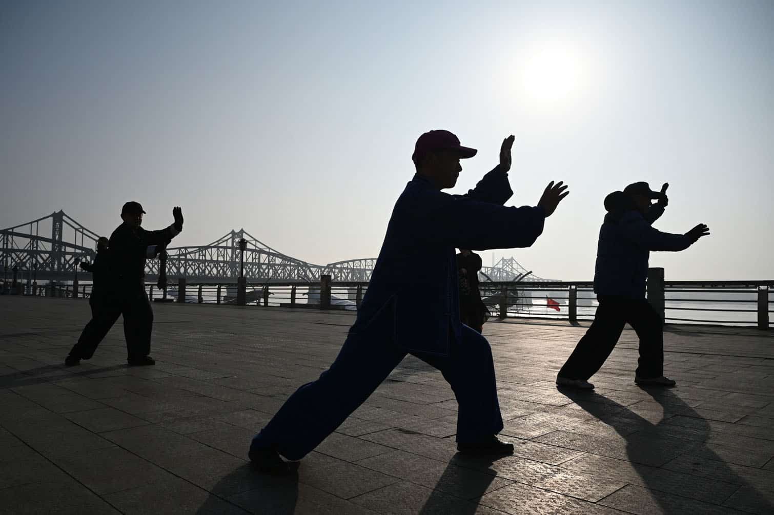 People perform Tai Qi on the waterfront of the Yalu river,