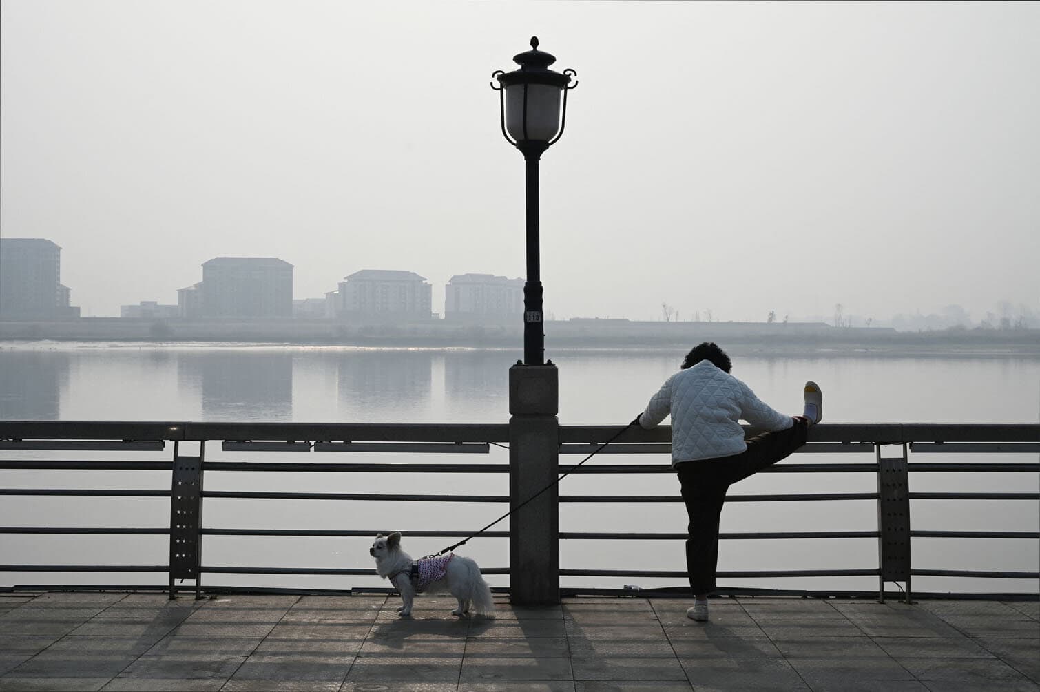 A woman exercises on the waterfront of the Yalu river
