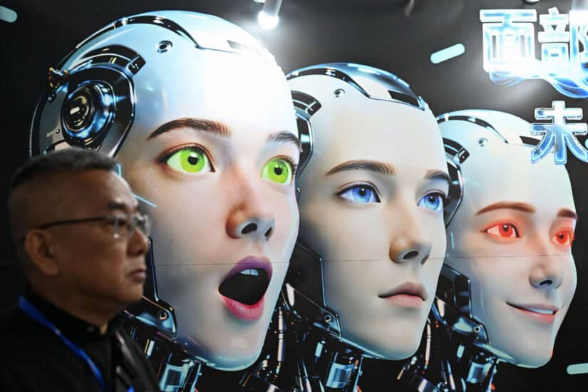 A man stands next to a poster showing robots