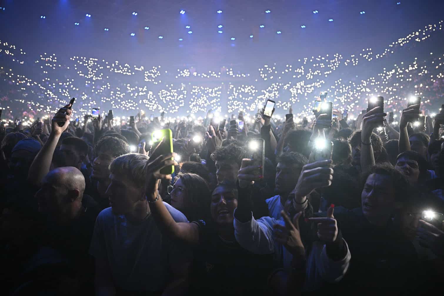 Fans hold smartphones with activated flashes during a concert