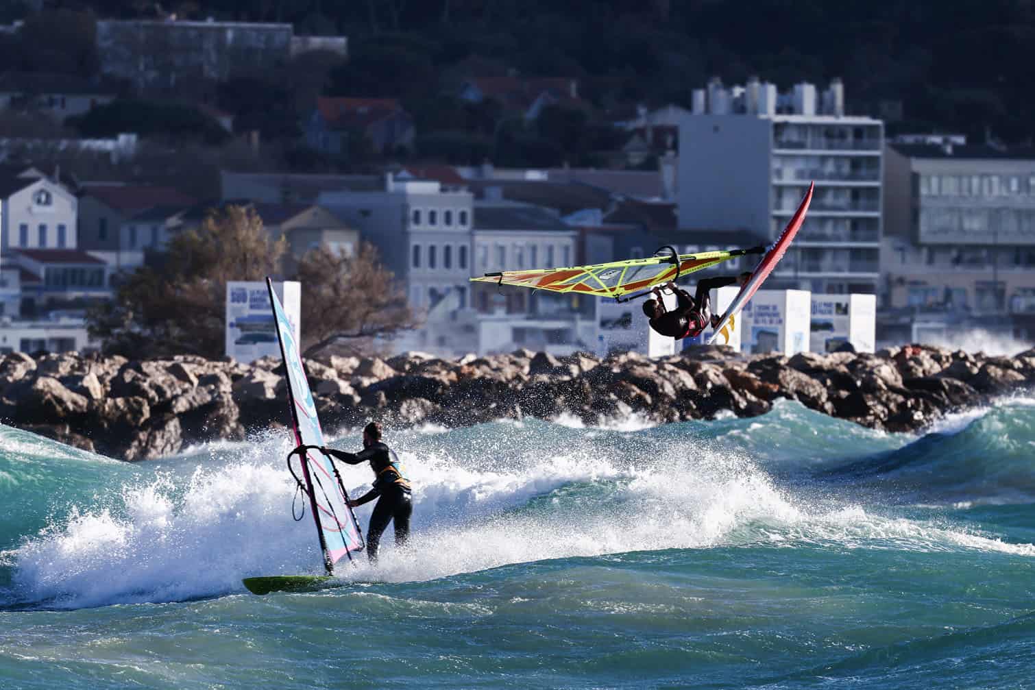 A windsurfer jumps over the waves