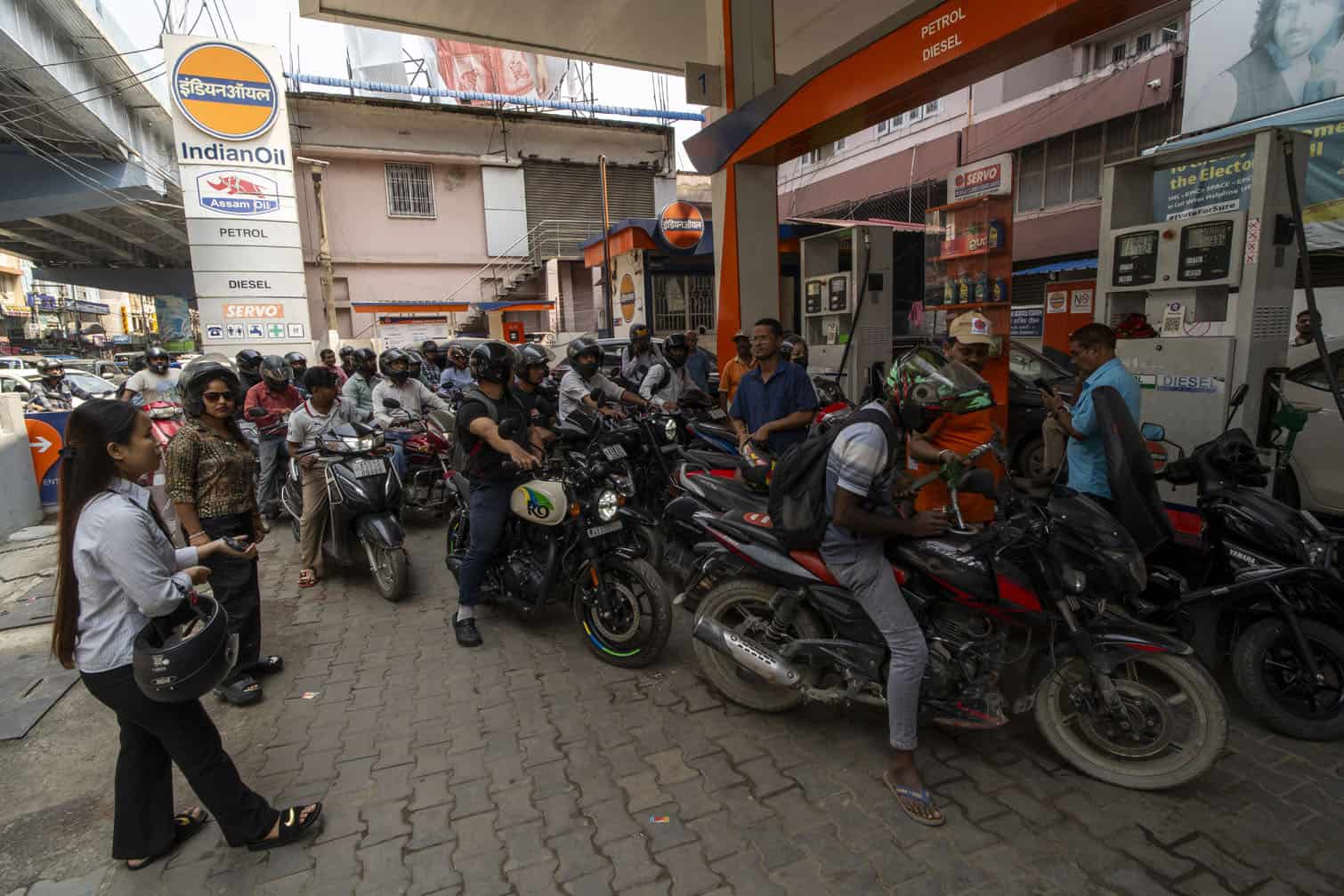 People stand in a queue to refill fuel at a gas station