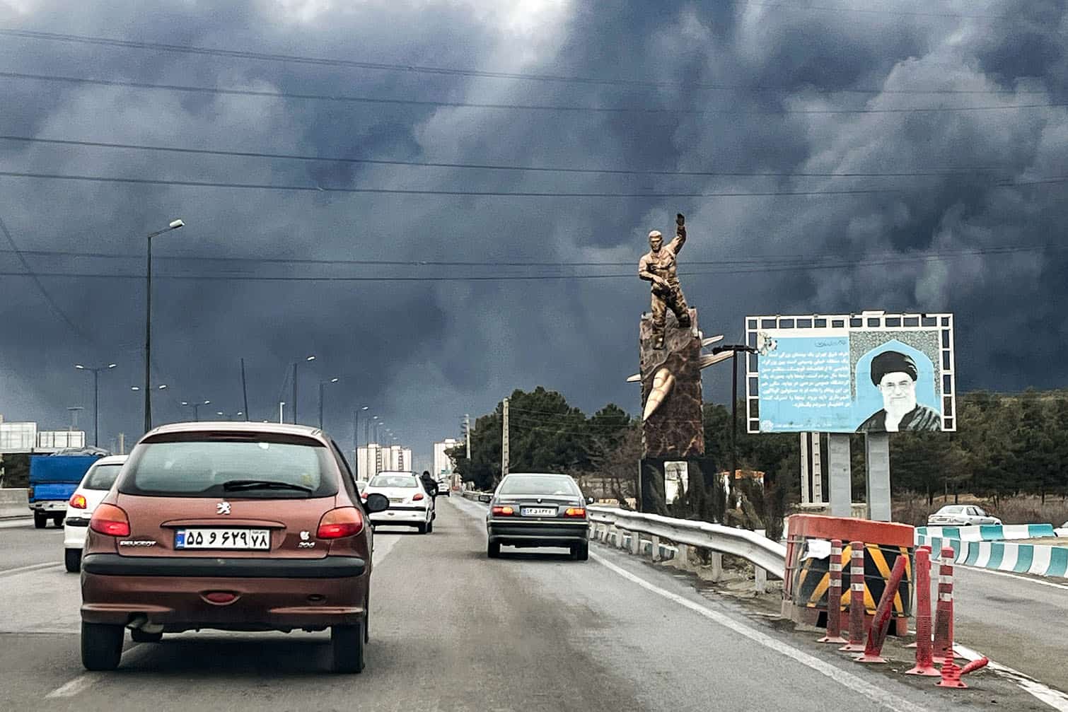 Vehicles move along a highway past a war memorial statue