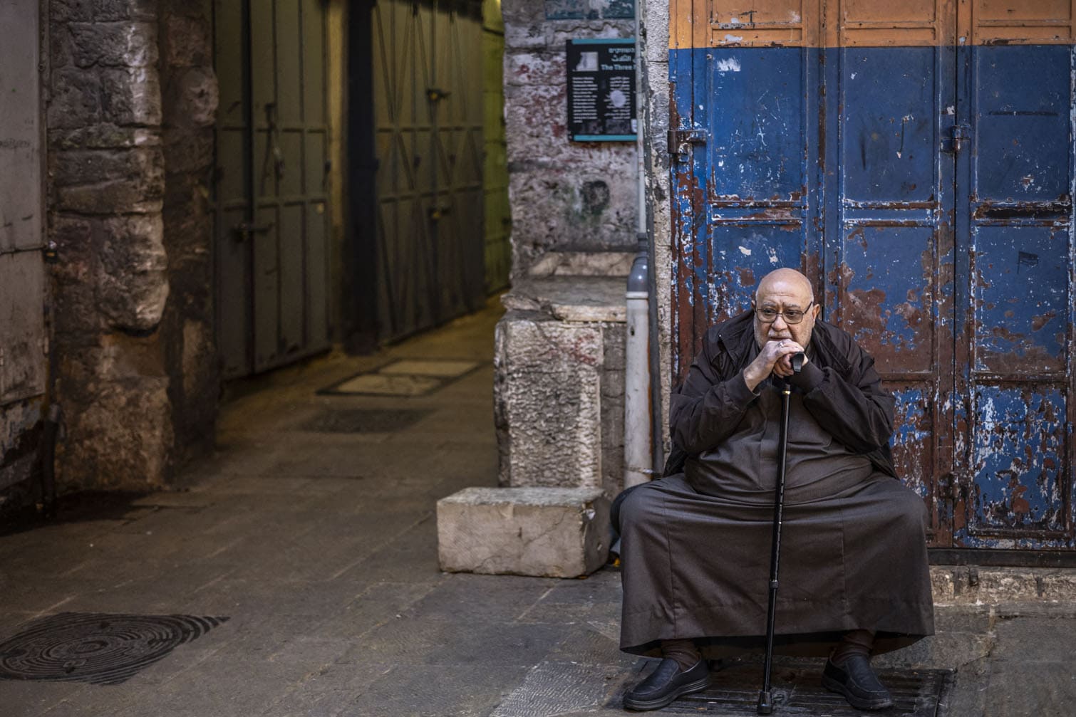 A man sits outside a closed shop in the the Old city of Jerusalem