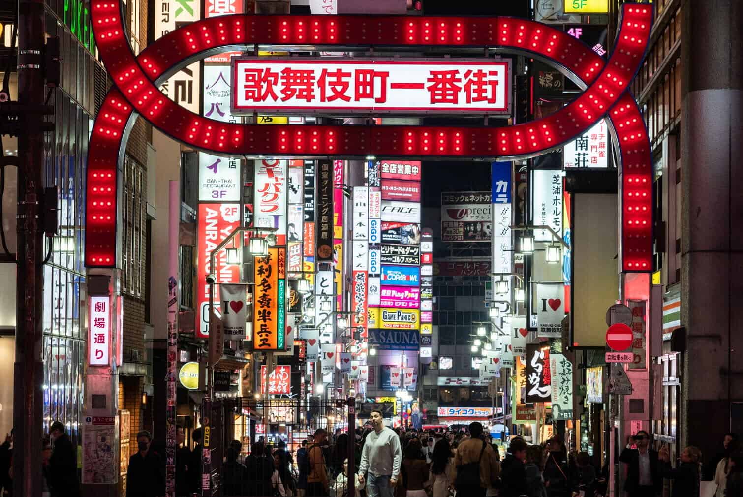 A man is illuminated as he looks up at a large neon sign