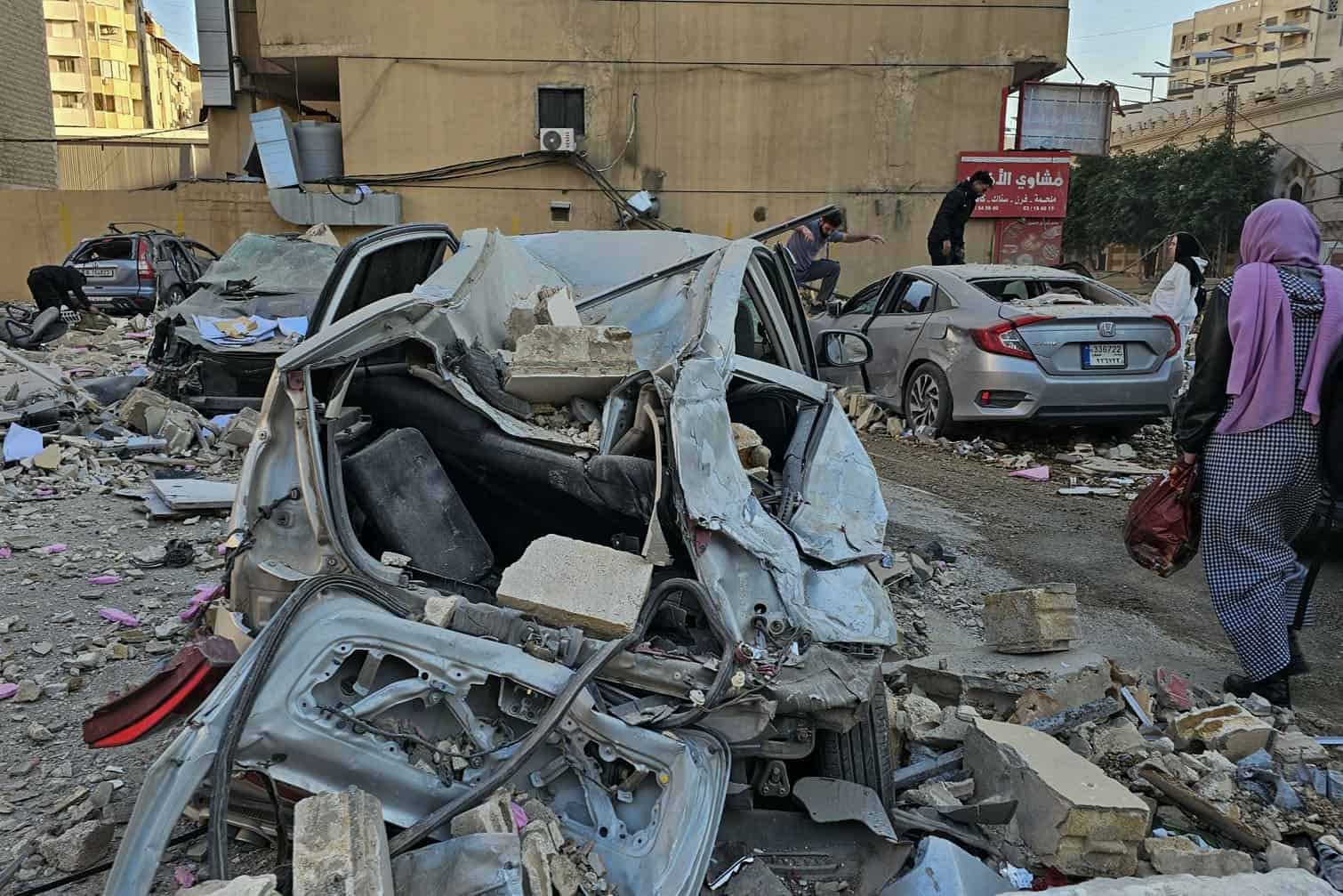 People check the wrecakge of cars damaged in an Israeli air strike