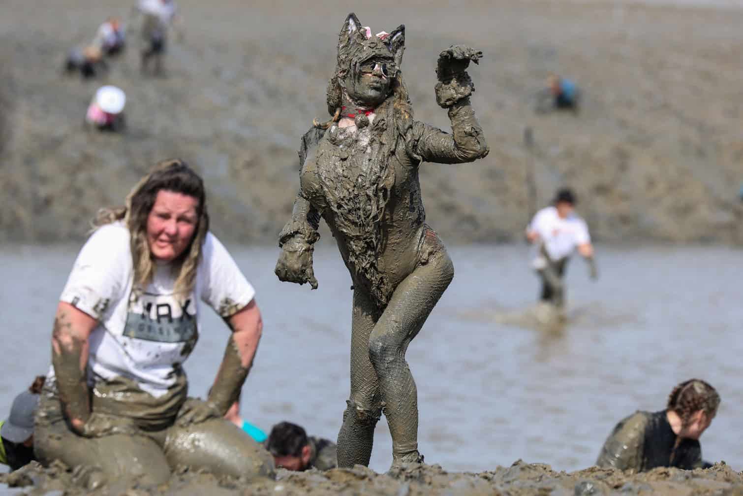 A participant poses, caked in mud