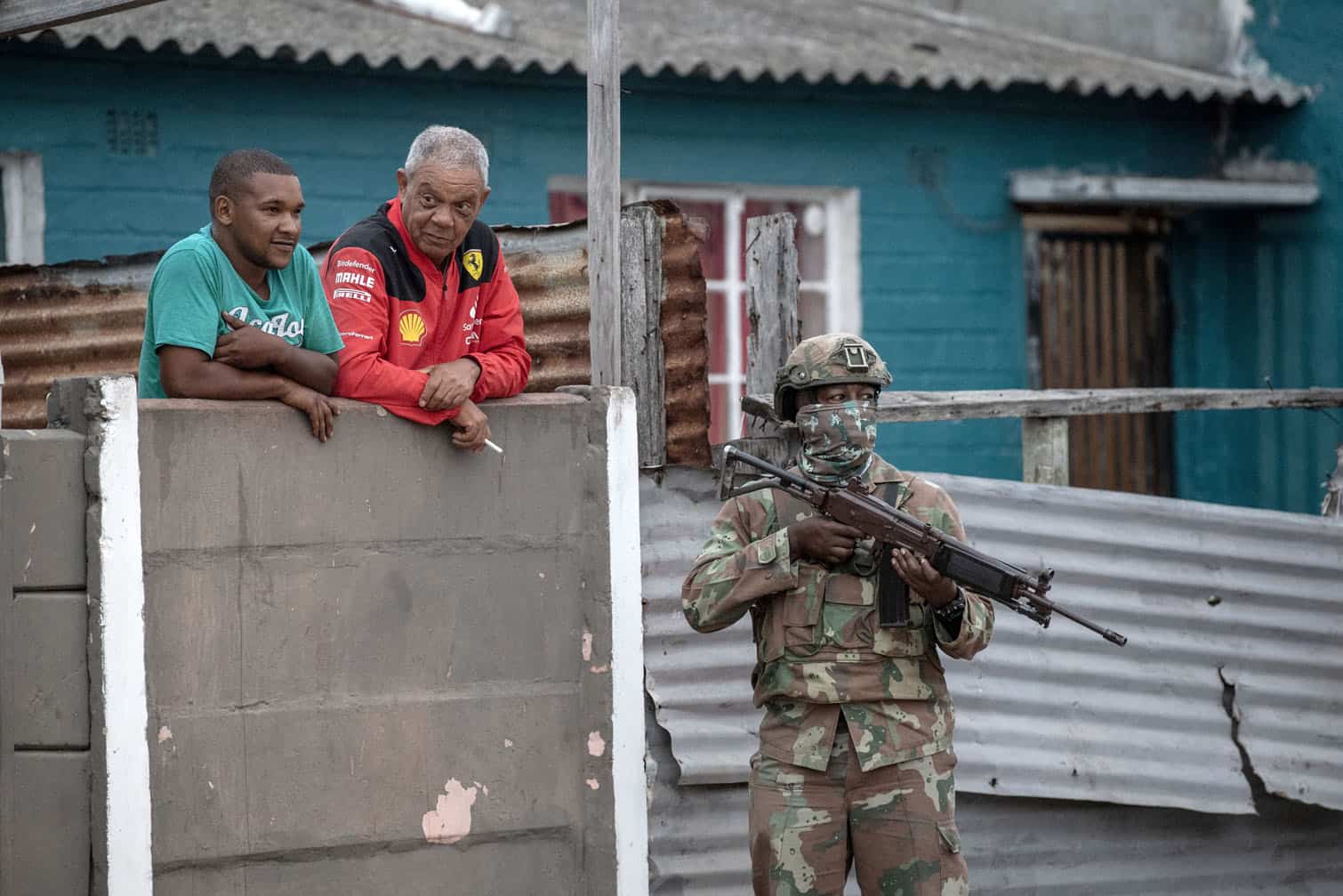 Two residents look on as a South African National Defence Force