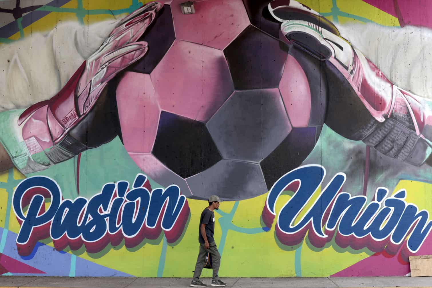 A man walks past a mural of a football player