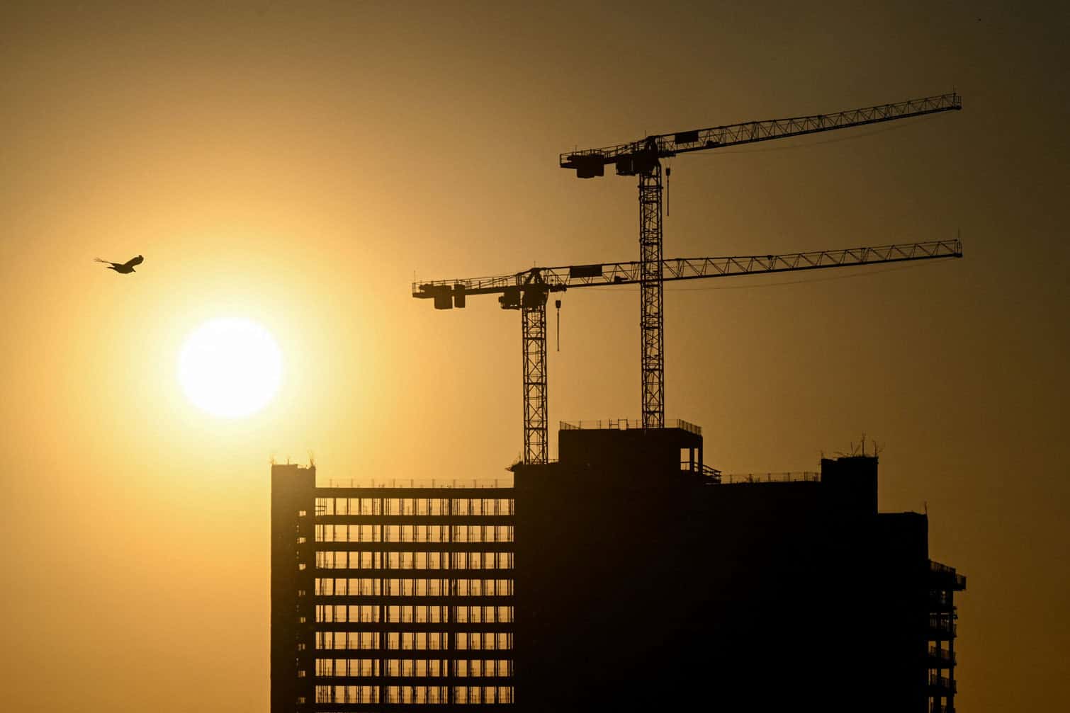 The sun rises behind a building under construction in Offenbach