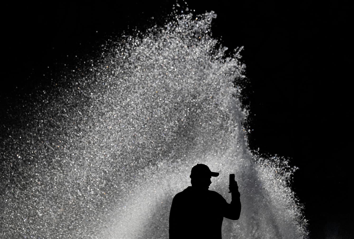 A man shoots a video on his mobile phone as a gust of wind scatters watter