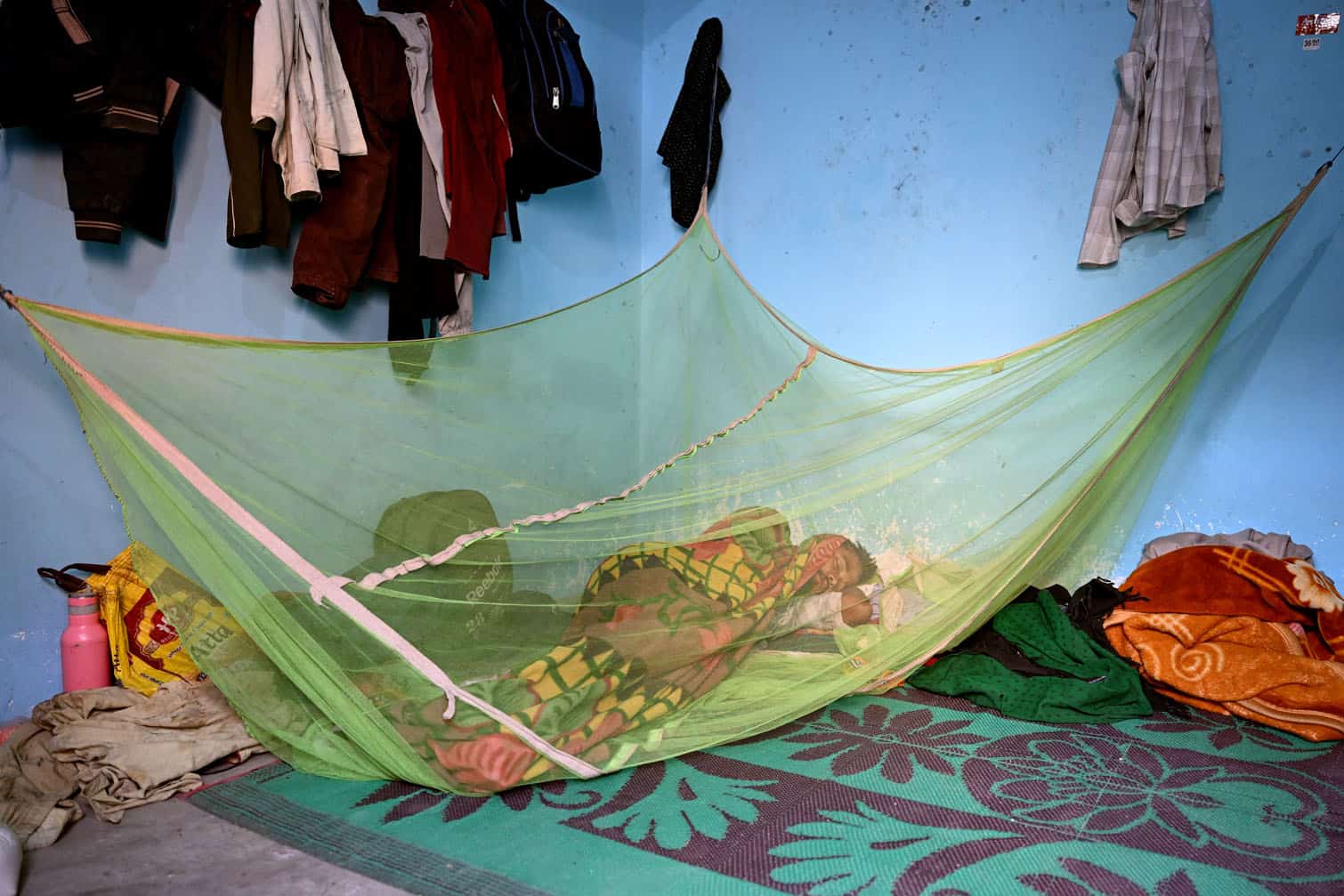 A migrant worker sleeps inside a mosquito net