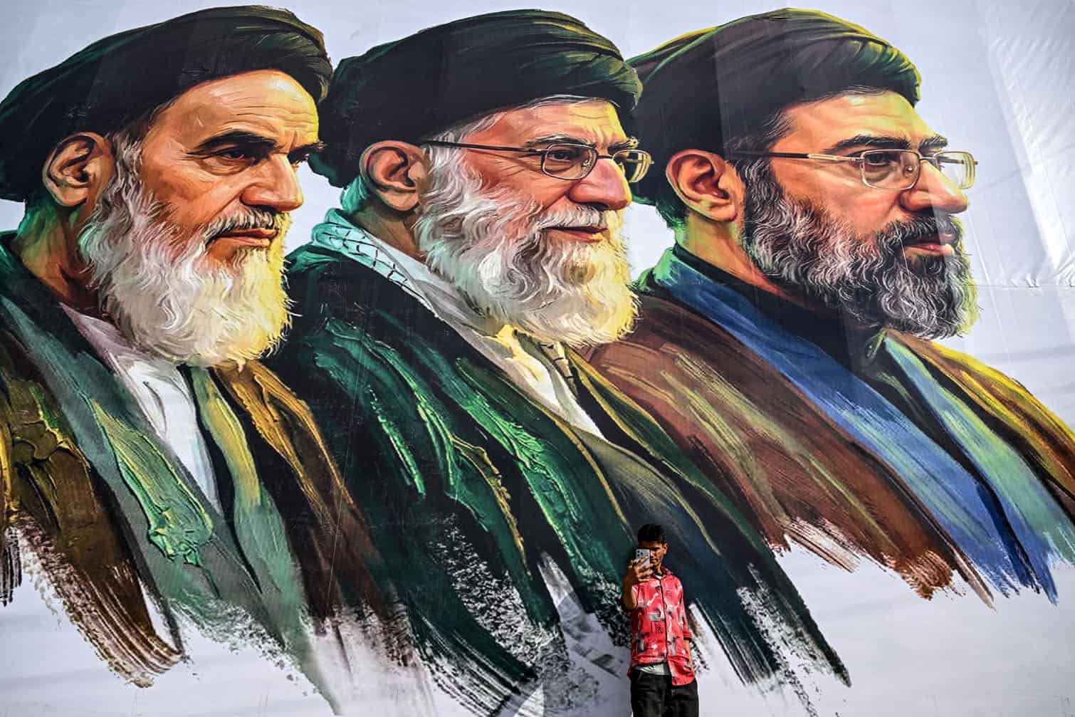 A man takes a selfie in front of a billboard