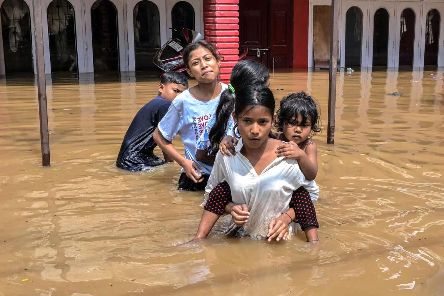 Children wade through floodwaters following heavy rainfall