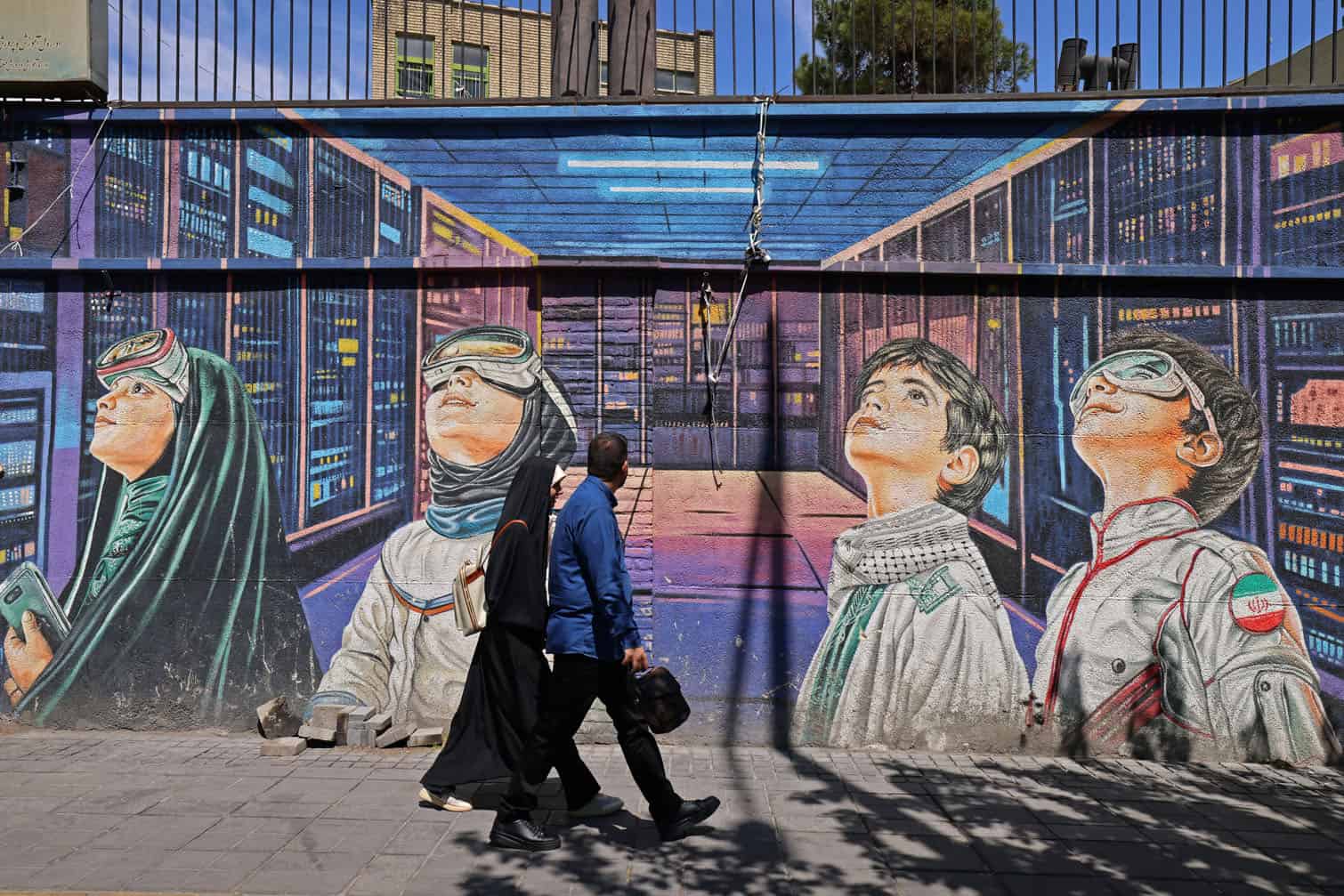People walk past a wall mural