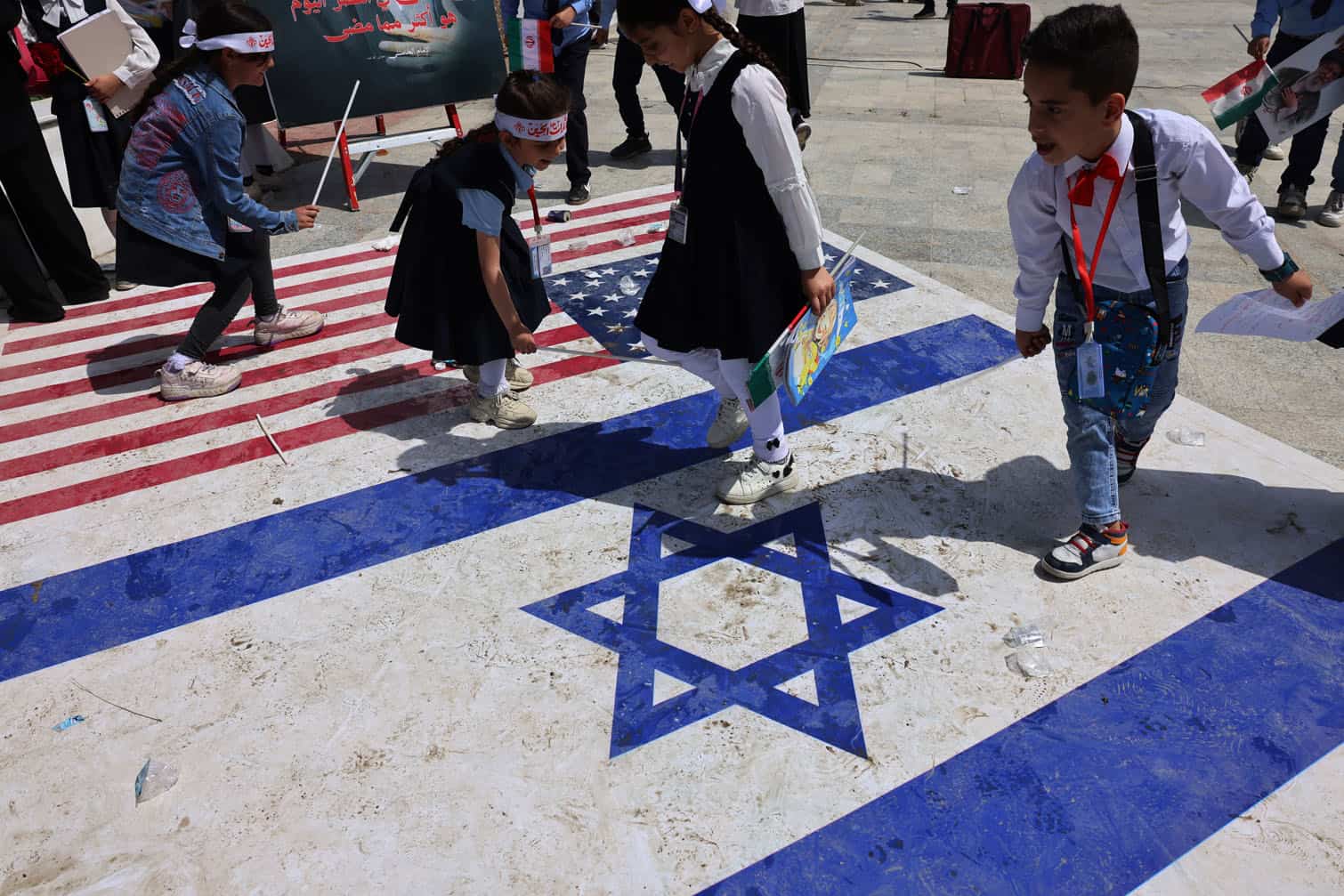 Iraqi school children play on US and Israel flags