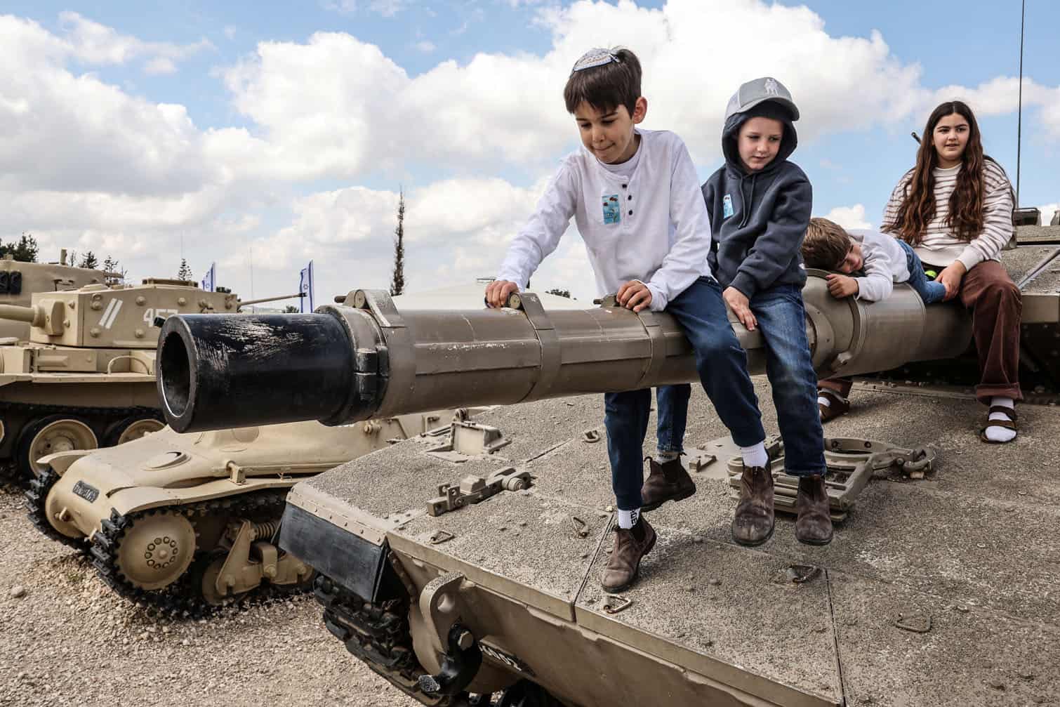 Children with their families climb atop old tanks and military vehicles
