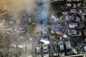 A firefighter walks past destroyed vehicles