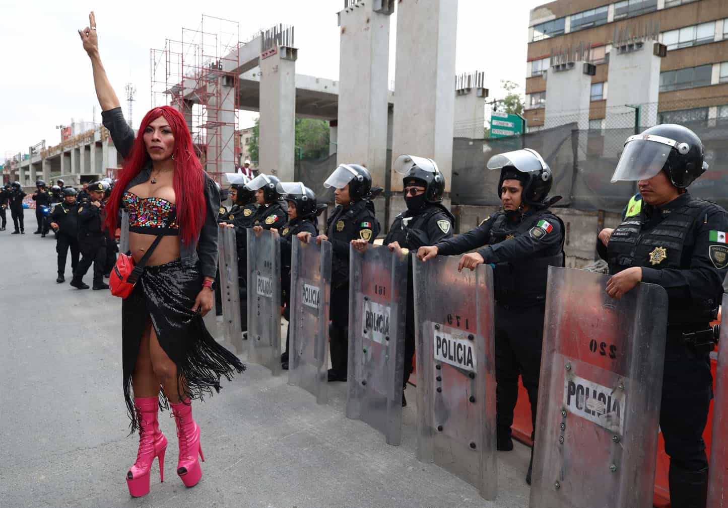 A transgender sex worker stands in front of Mexican riot police