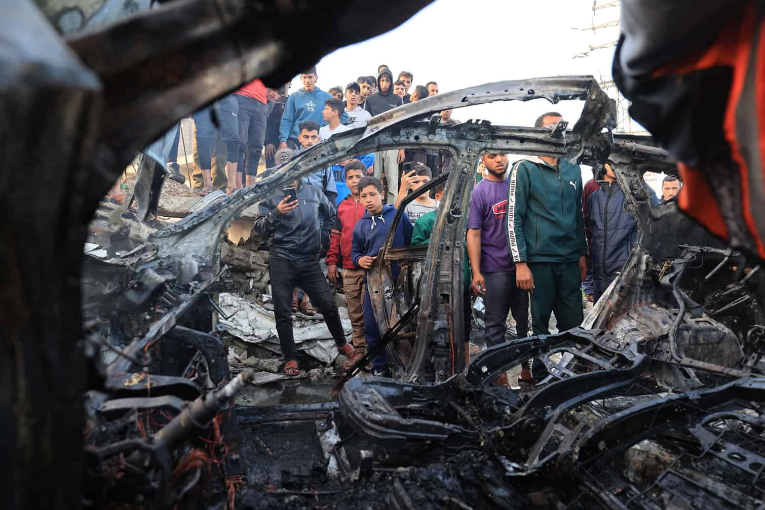 Palestinians inspect a vehicle targeted by an Israeli strike