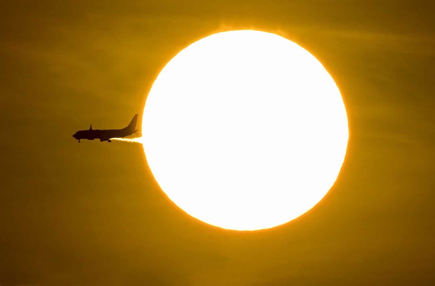 An airplane passes in front of the sun