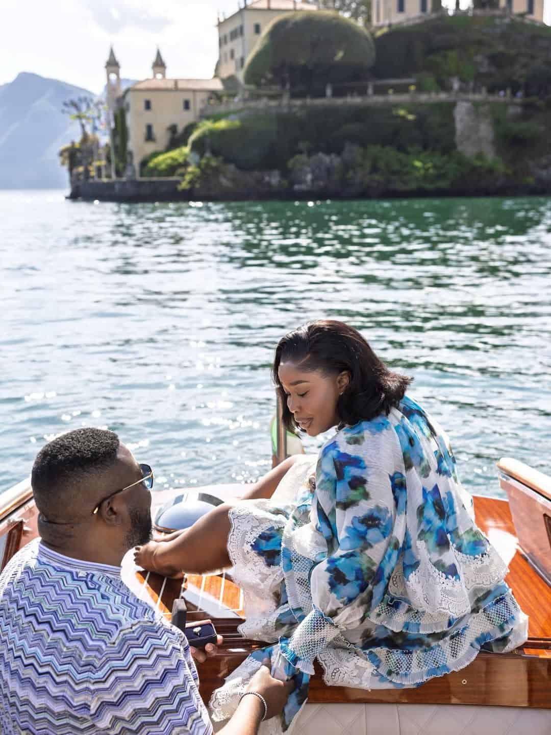 Young woman and man on a boat enjoying a scenic lake view in Italy.